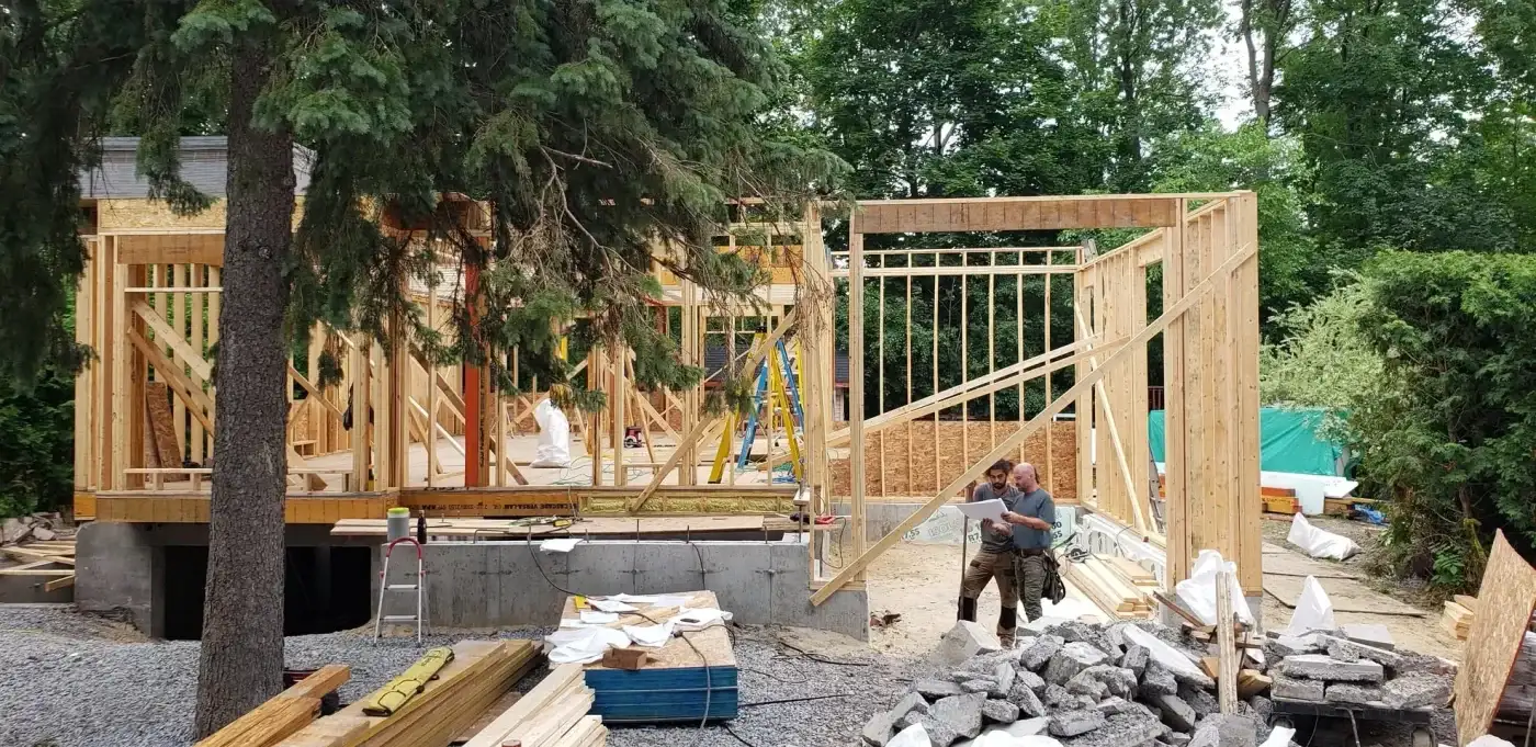 Les deux charpentiers de l'Atelier de la Poutre Tordue devant un plan de chantier déplié