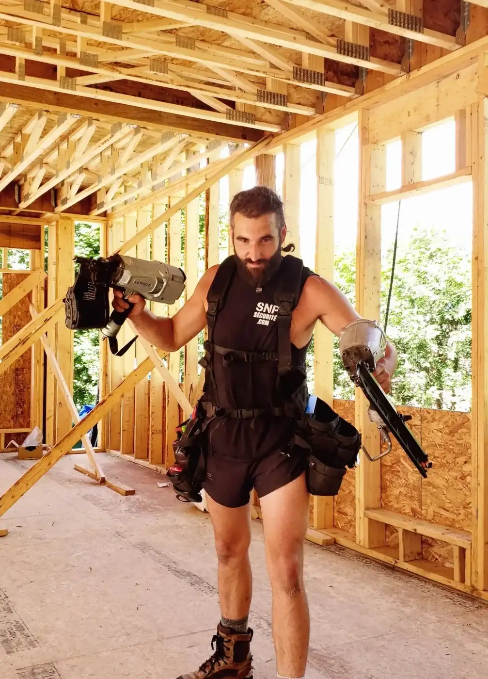 Christopher Auger-Labelle sur un chantier, une cloueuse dans chaque main