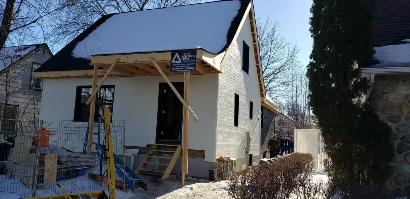 Auvent de bois neuf posé sur une façade blanche fraîchement revêtue