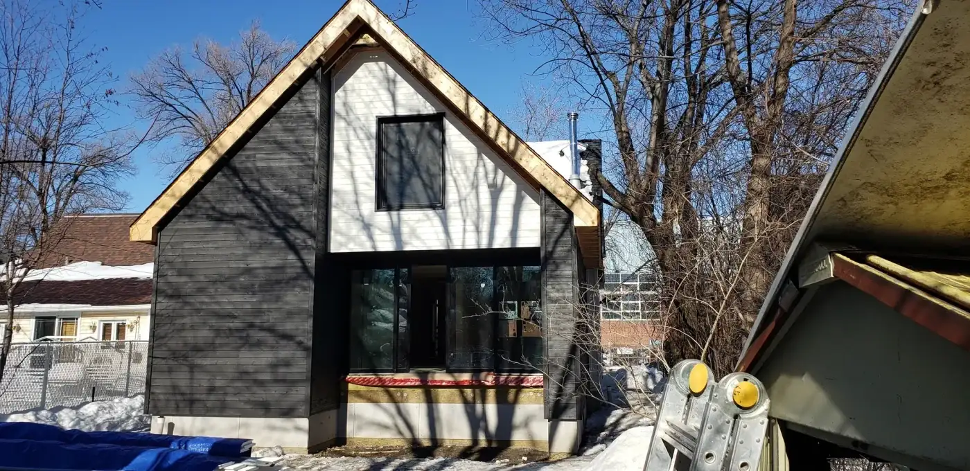Façade terminée avec revêtement de bois noir et blanc, fenêtres encadrées et solins posés