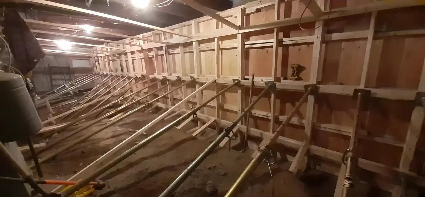 Coffrage de béton et étais métalliques installés dans un sous-sol pour reprendre un point d’appui