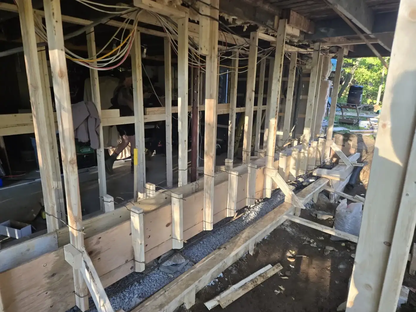 Maison étayée sur vérins pendant qu'une semelle de béton neuve est coulée sous la fondation existante